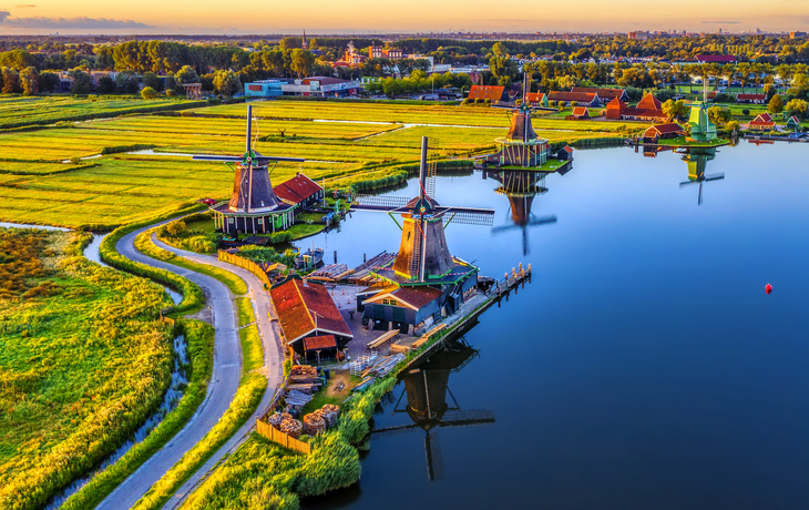 Historische Windmühlen an einem Fluss bei Sonnenuntergang.