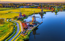 Historische Windmühlen an einem Fluss bei Sonnenuntergang.