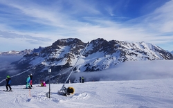 Berglandschaft im Winter mit Skifahrern und verschneiten Gipfeln.