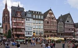 Fachwerkhäuser und ein gotischer Kirchturm auf einem belebten Platz in Frankfurt am Main.