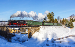 Eine historische Dampflok der Fichtelbergbahn fährt im Winter durch die schneebedeckte Landschaft des Erzgebirges von Cranzahl nach Oberwiesenthal.