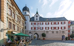 Historisches Stadttor mit angrenzendem Café und Personen im Freien.