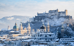 Winterlicher Blick auf die Festung Hohensalzburg und die verschneite Altstadt von Salzburg.