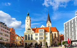 Rathausplatz in Ingolstadt, Bayern, mit historischem Rathausgebäude vor blauem Himmel.