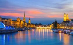 Innenstadt von Zürich in der Schweiz bei Dämmerung im Winter mit Blick auf die Altstadt und den Fluss Limmat.