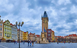Panoramablick auf den Altstädter Ring in Prag mit historischen Gebäuden und dem Turm der astronomischen Uhr bei bewölktem Himmel.