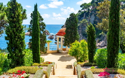 Terrasse mit Blick auf das Meer, gesäumt von Zypressen und mediterranen Pflanzen.