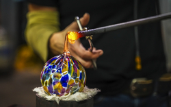 Glasbläser formt bunte Glaskugel mit heißem Glas.