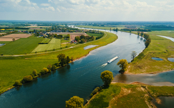 Landschaft mit Fluss, Feldern und einem Boot aus der Vogelperspektive.