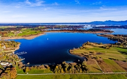 Luftaufnahme eines Sees mit umliegender Landschaft und blauem Himmel.