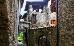 Gasse in einem alten Steindorf mit gewölbten Fenstern und Türen.