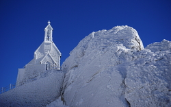 Schneebedeckter Gipfel des Wendelsteins in den Bayerischen Voralpen mit einer Kapelle im Winter.