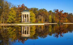 Apollotempel im Schlosspark mit Herbstbäumen und See im Vordergrund.