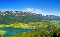 Panorama des Kalterer Sees mit umliegenden Bergen und Weinbergen.