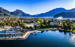 Panorama einer Stadt am See mit Bergen im Hintergrund bei strahlendem Sonnenschein.