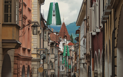 Schmale Gasse mit historischen Gebäuden und grünen Straßenlaternen.