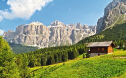 Berghütte vor einer Sommerlandschaft mit Bergen im Hintergrund