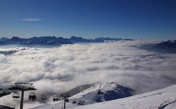 Berglandschaft mit Wolken und Sessellift im Vordergrund.