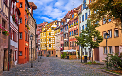 Fachwerkhäuser und eine gepflasterte Gasse in der Altstadt von Nürnberg, Bayern, Deutschland bei sonnigem Wetter.
