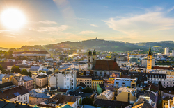 Stadtpanorama mit Kirchturm und Hügel im Sonnenuntergang.
