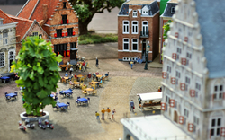Miniatur-Modell einer Stadtplatzszene mit Tischen und Menschenfiguren.