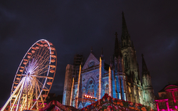 Riesenrad und beleuchtete Kirche bei Nacht auf einem Jahrmarkt.