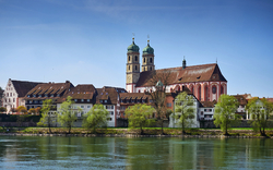 Stadtansicht mit Kirche und Fluss im Vordergrund.
