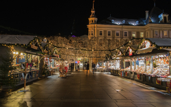 Beleuchteter Weihnachtsmarkt bei Nacht mit geschmückten Ständen und Lichtern.