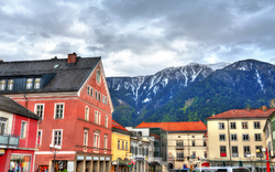 Stadtansicht mit bunten Gebäuden und Bergen im Hintergrund.