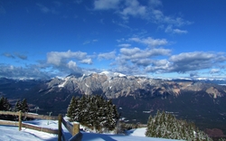 Verschneite Berglandschaft mit bewölktem Himmel.