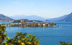 Blick auf eine Insel im See, umgeben von Bergen und Palmen im Vordergrund.