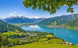 Panoramablick auf einen See, Berge und eine Stadt im Tal bei sonnigem Wetter.