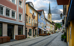Historische Straße mit bunten Häusern und Kirchturm im Hintergrund.