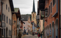 Straßenszene in einer deutschen Stadt mit Kirchturm im Hintergrund.