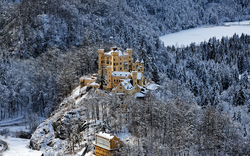 Schneebedecktes Schloss in winterlicher Waldlandschaft.
