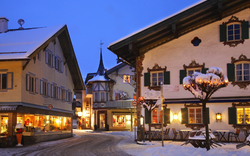 Verschneite, beleuchtete Altstadtstraße mit Fachwerkhäusern bei Abenddämmerung.