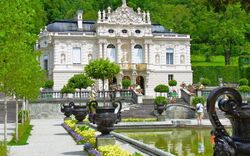 Schloss Linderhof mit dekoriertem Garten und Brunnen im Vordergrund.