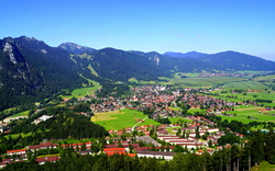 Panorama einer Stadt in einer grünen Berglandschaft.
