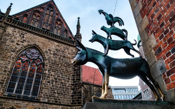 Skulptur der Bremer Stadtmusikanten vor historischer Kirche in Bremen, Deutschland.