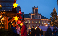 Weihnachtsmarkt in Weimar mit beleuchteten Ständen und Menschen im Abendlicht.
