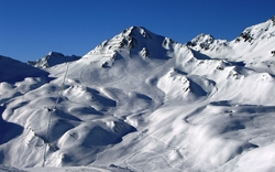 Schneebedeckte Berglandschaft unter klarem blauen Himmel.