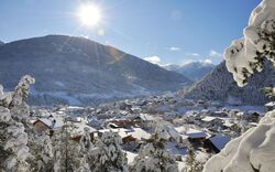 Verschneites Dorf im Pitztal mit Bergen und Sonne im Hintergrund.