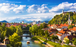 Stadtpanorama mit Fluss, Brücke und Hügel mit Schloss im Hintergrund.