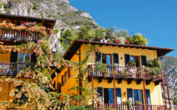 Gelbes Haus mit Blumen geschmückten Balkonen in einer malerischen Berglandschaft.